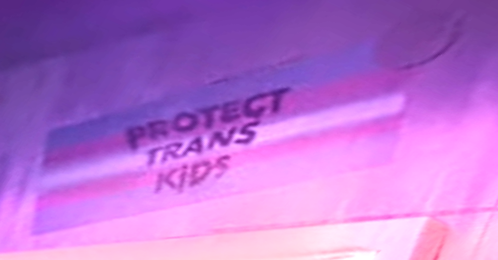 Same screenshot but zoomed all the way in to the trans pride flag. The tagline “protect trans kids” is clearly visible.

The screenshot has been altered with increased contrast and sharpness and brightness to underline the “enhance” move trope.