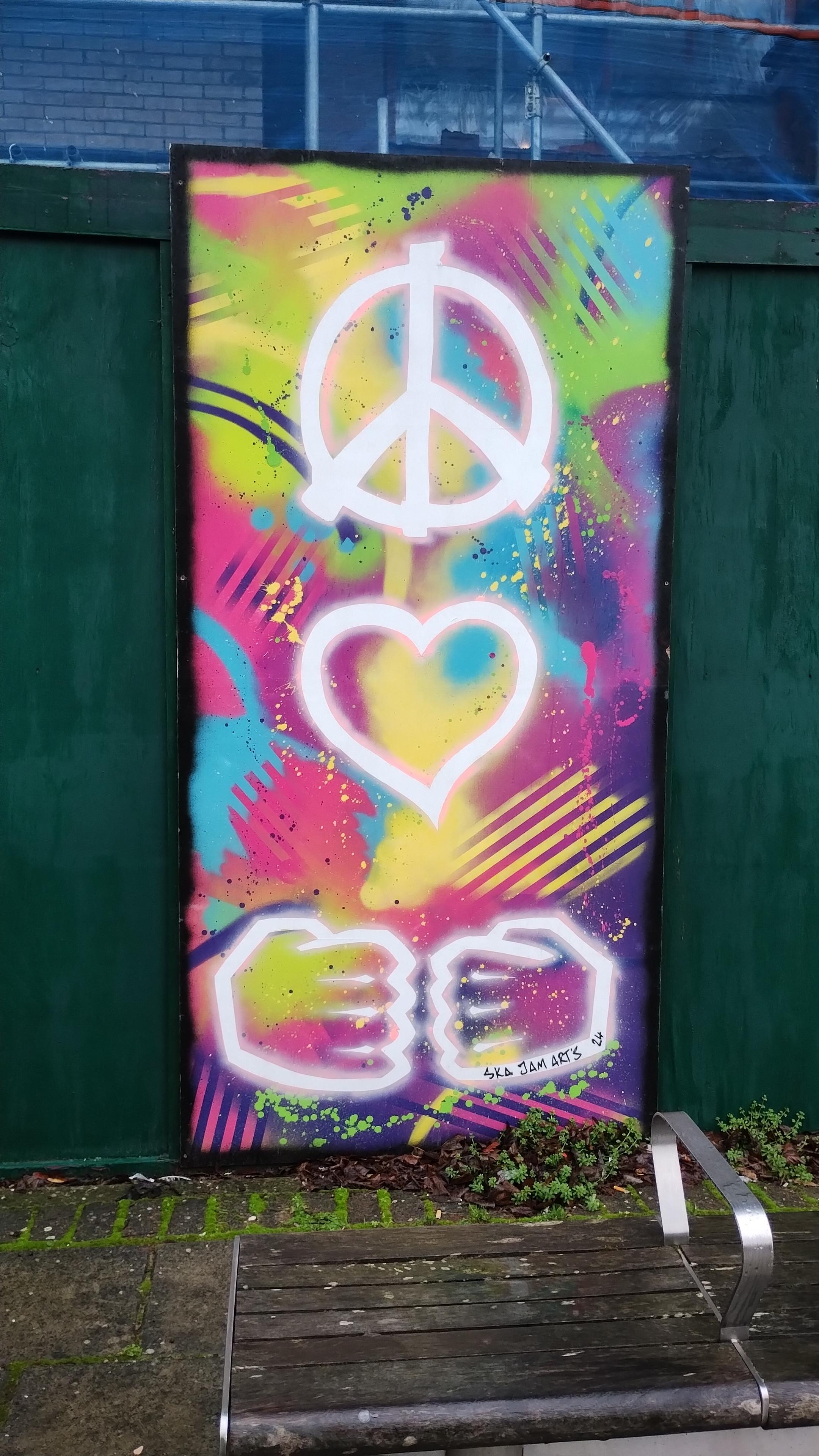 Some street art that shows a peace sign, a heart and then two hands that could be a fist bump or the goatse hands.